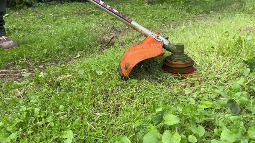 Gasoline scythe mows grass on the lawn | Shutterstock HD Video #1096981789