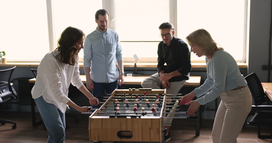 Group of diverse businesspeople having great time together during break. Happy carefree office employees, older and younger workmates play table soccer or foosball in workplace, enjoy victory and rest Royalty-Free Stock Footage #1096987945