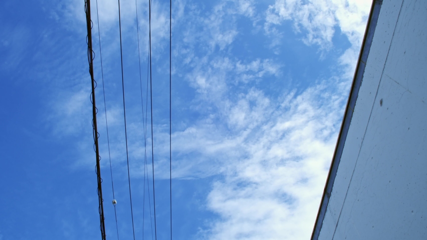 Poles and wires Moving shot under clouds and blue sky