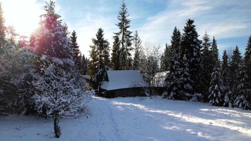 Magical winter snowy white landscape. Snow capped spruce trees and huts in the mountains. Beautiful mountain chalet or cabin in the middle of the winter forest covered with snow.