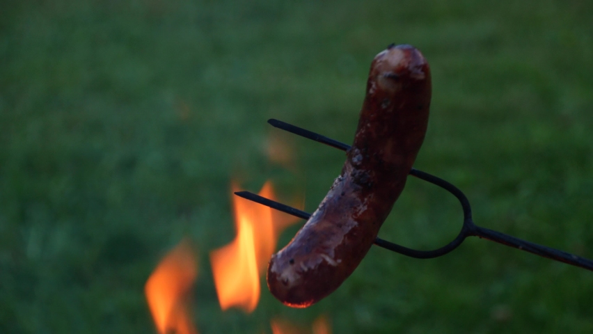 Campfire in the nature. Roasting sausages on a campfire. Bonfire at the campground on a warm summer evening.. 