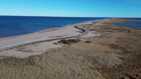 Aerial drone clip of the Bouctouche Sand Dunes and boardwalk along the beach, running alongside the Atlantic Ocean.