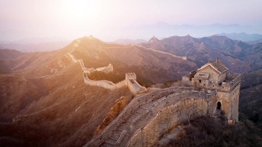 Aerial shot of the Great Wall of China at sunset on a hazy day.