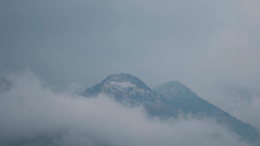 Clouds below the snow covered Himalayan mountains during the snow storm at Manali in Himachal Pradesh, India. Clouds cover the mountain during the storm. Winter background of snowfall in mountains.  | Shutterstock HD Video #1096997115