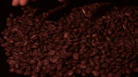 Man pouring coffee beans with his hand, slow motion and black background.