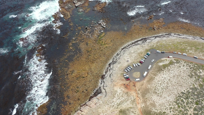 Descending down to the famous "Cape of Good Hope" area with the nearby parking space. People walking around the most south-western point of the African continent. South Africa aerial video view  - K4