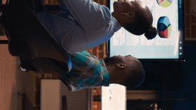 Vertical video: Diverse coworkers brainstorming in business meeting, discussing analytics presentation. Colleagues communication, people talking in coworking space boardroom at night time - Powered by Shutterstock - Get 15% off with code: PIKWIZARD15