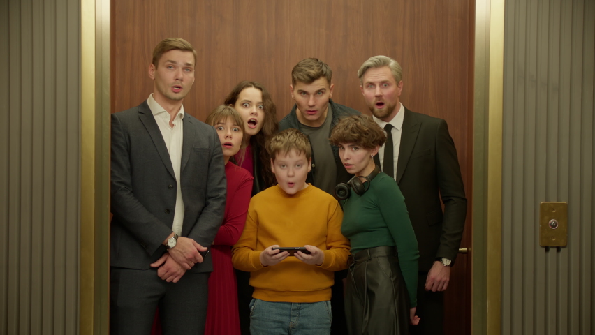 ZOOM IN Surprised Kid boy is using his smartphone in the elevator, everybody watching the screen | Shutterstock HD Video #1097004131