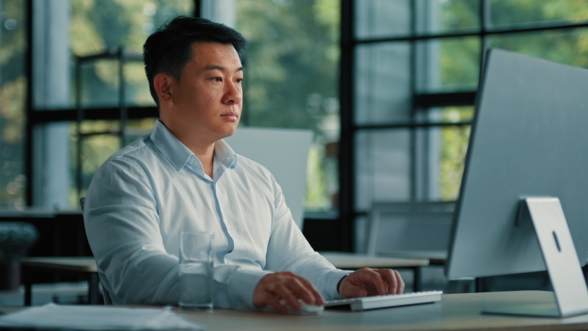 Asian korean man drink glass of cold fresh water keep health balance rejuvenation energy healthcare habit businessman sit at office work on computer make pause quench thirst body hydration bodycare Royalty-Free Stock Footage #1097004277