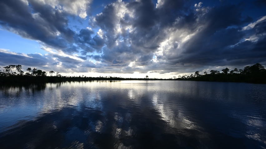 Timelapse of active sunset cloudscape over Pine Glades Lake in Everglades National Park, Florida reflected in still waters of lake 4K.