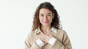 Happy grateful pleased young pretty smiling woman putting hands on chest expressing sincere gratitude, warm appreciation, thanking or feeling touched standing at white background. - Powered by Shutterstock - Get 15% off with code: PIKWIZARD15