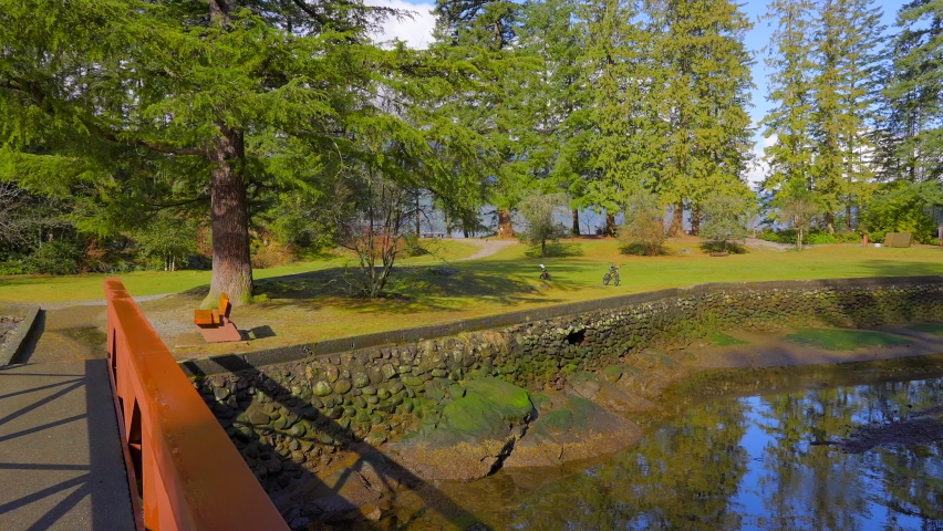 Establishing shot of park at ocean beach with rocks and pebbles in slow motion at summer day in Vancouver, Canada, North America. Day time on September 2022. Still camera. ProRes 422 HQ.