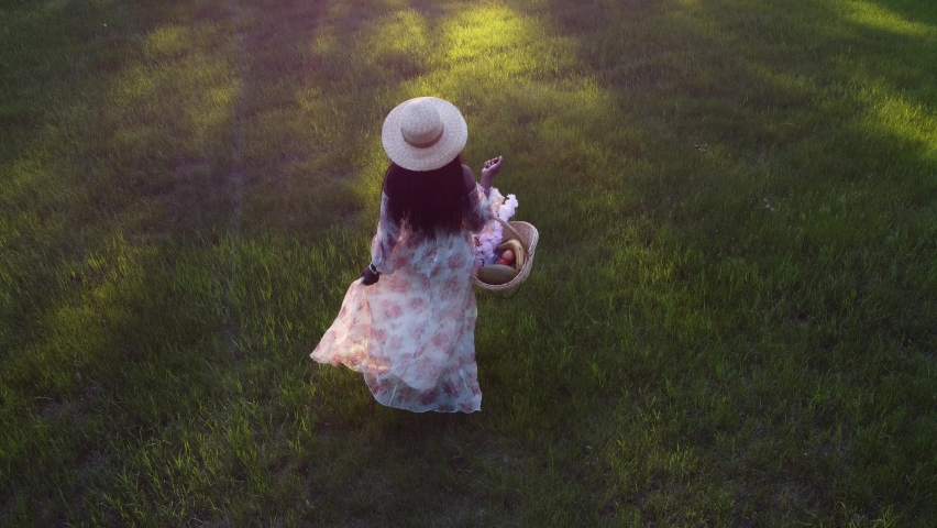 Black Woman with basket walking in park with flare drone followed