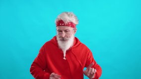 Adult gray-haired hipster in a red hoodie dancing to the music on a blue background, a cheerful man is filmed in a video for advertising.