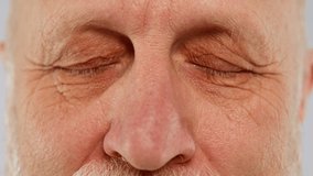 Elderly man with deep wrinkles on face opens tired grey-blue eyes blinking - Powered by Shutterstock - Get 15% off with code: PIKWIZARD15