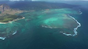 Drone flight over the island of Mauritius in the Indian Ocean. Underwater waterfall in a coral reef from a bird's eye view. Turquoise water is the dream of a tourist and traveler