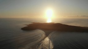 Still drone video of Shark island, Fingal Bay at sunrise, with low waves crashing over the spit sand bar