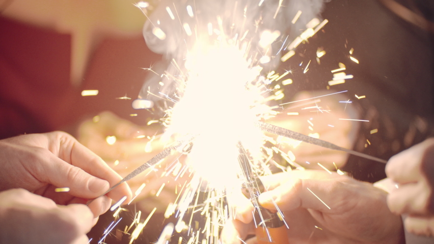 Beautiful woman holding christmas sparklers in hands. Friends celebrating by waving fireworks, enjoying party on New Years or Christmas Eve night. Happy group of people enjoying party in Xmas evening. Royalty-Free Stock Footage #1097020753