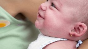 Close-up slow-motion 4K video of a mother feeding her baby a fruit puree, beginning complementary feeding after six months. Introduction of solids in the infant diet.
