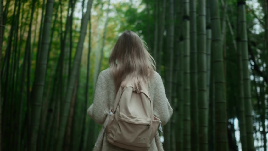 Blond tourist woman walking through bamboo forest