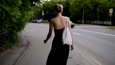 Beautiful young woman walking down the street. Handheld footage.の動画素材
