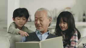 asian grandpa reading book together with two grandchildren - Powered by Shutterstock - Get 15% off with code: PIKWIZARD15