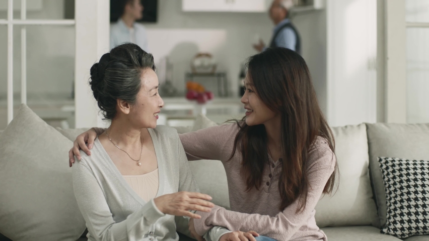young asian woman chatting with senior mother during visit while the two husbands talking in background Royalty-Free Stock Footage #1097031491