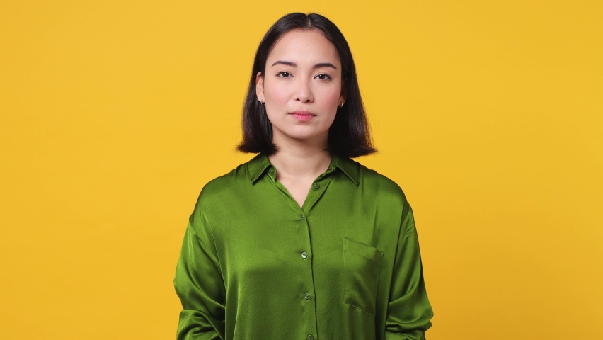 Serious strict severe young woman of Asian ethnicity 20s she wear casual green shirt say no hold palm folded crossed hand in stop gesture isolated on plain yellow color wall background studio portrait Royalty-Free Stock Footage #1097031979
