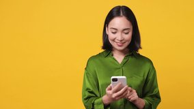 Young woman she wear green shirt get video call hold use mobile cell phone doing selfie conducting pleasant conversation greet with hand isolated on plain yellow color wall background studio portrait
