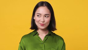 Beautiful toothy smiling charming friendly young woman of Asian ethnicity 20s she wears satin green shirt looking camera wink eye blink isolated on plain yellow color wall background studio portrait - Powered by Shutterstock - Get 15% off with code: PIKWIZARD15
