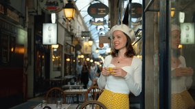 Young woman drinking coffee in a Parisian gallery indoors