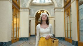 Smiling girl in a yellow skirt walking in a Parisian gallery