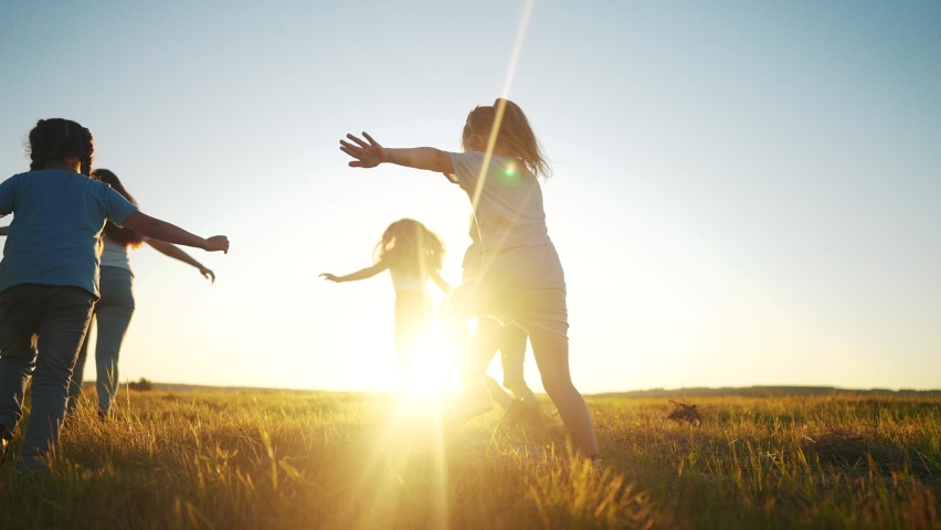 kids run in the park at sunset. friendly family children camp kid dream concept. a group of children run on fun the grass at the rays of the sun silhouette. childhood sunset dream teamwork concept Royalty-Free Stock Footage #1097039453