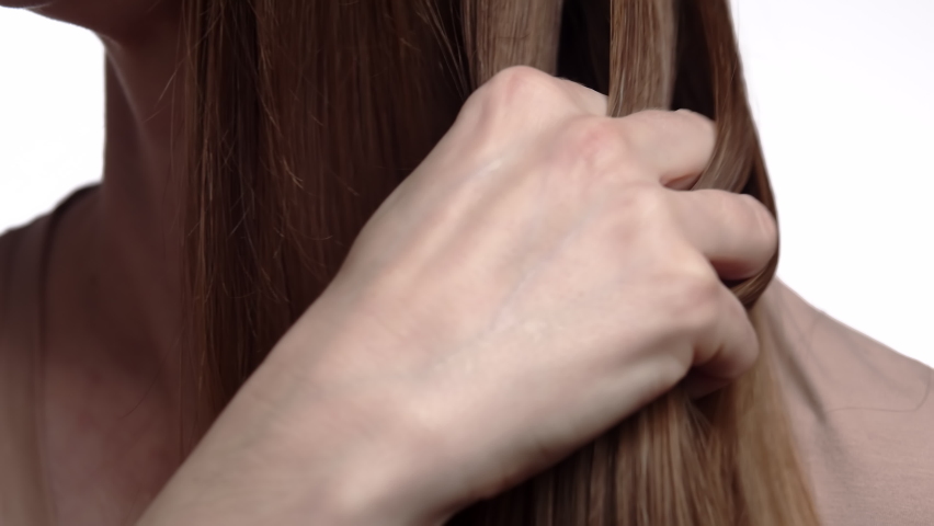 Close-up. Caucasian woman runs her hand through her hair, emphasizing the beauty and shine hair. The girl shows her healthy hair falling over shoulders. Royalty-Free Stock Footage #1097044215