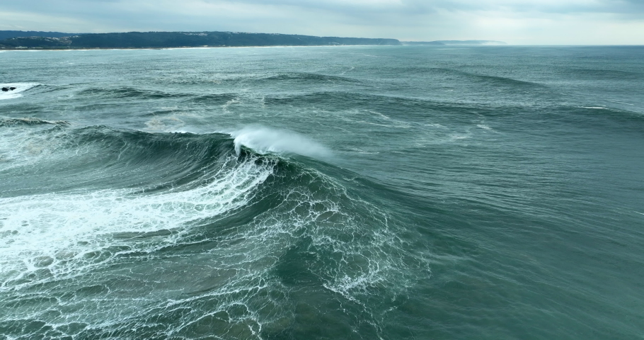Aerial view of powerful dark ocean waves rolling from above. Drone flying over fabulous sea tide on a stormy day. Breaking surf with foam in Atlantic ocean. Big swell in Nazare, Portugal. Royalty-Free Stock Footage #1097044669