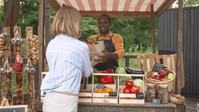 Portrait of contented happy female buyer taking paper bag with fresh eco products from senior man farmer in apron selling food at stall at local market. Satisfied customer. Food business concept - Powered by Shutterstock - Get 15% off with code: PIKWIZARD15