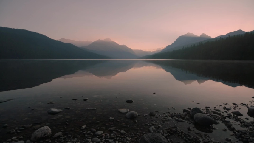 The water in Bowman lake, Glacier National park Montana ripples gently in the warm soft light of early morning before the sun rises over the distant mountains.