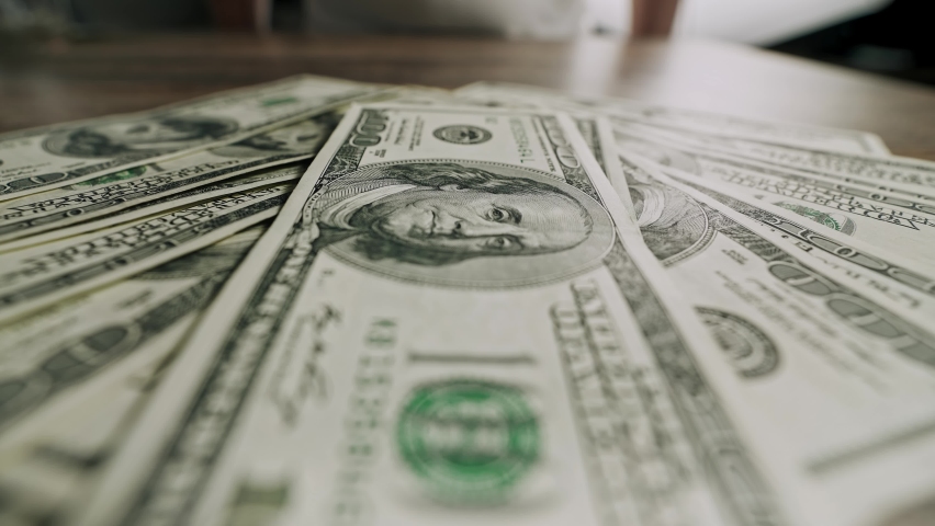 Close-up of American dollars in the hands of a man. Bucks, bills, Cash, Wages.  The concept of success, the economy, money won at the casino. A man grabs a pile of dollars lying on the table. Royalty-Free Stock Footage #1097047841