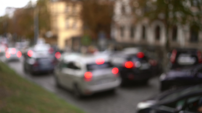 Cars In Traffic. Car traffic in a city street road. Defocused footage of parked and moving cars on background at dusk. Dense city traffic, cars are moving slowly, traffic jam. 4k video