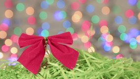 Red bow and green tinsel on the background of Christmas lights. Place to copy. New Year multi-colored lights in defocus. Beautiful holiday card, video for intro, text, intro. UHD 4K.