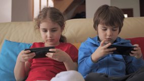 Kids Playing Video Game on Mobile Phone. Boy and Girl Plays Video Game Smartphone on Sofa Friends Using Phone for Gaming Online Education Social Media Children Playing Games In Phone at Home on Couch.