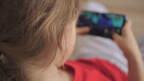 Kid Using Phone for Gaming Online Education Social Media. Child Playing Games In Phone at Home Sitting on Couch. Girl Playing Video Game on Mobile Phone. Teenager Plays Video Game Smartphone on Sofa.