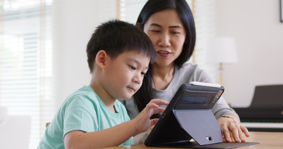 Cute asia people alpha Gen Z kid small boy play video game app online happy mum at home. Enjoy Child care fun class little son and mom study learn upskill idea course on smart digital tablet computer. Royalty-Free Stock Footage #1097069635