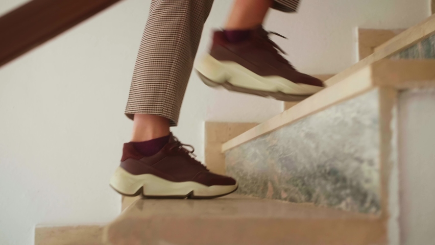 Active woman in sneakers climbing stairs. Close up of female legs walking stairs, cardio exercises training.