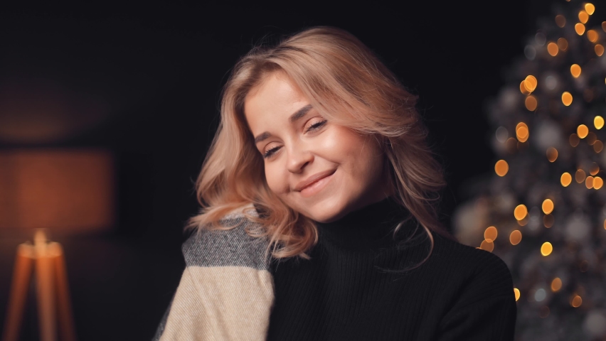 Close up portrait of incredible happy attractive young blonde woman woman against Christmas tree background at home in the evening, smiling hard at camera, happy and cheerful