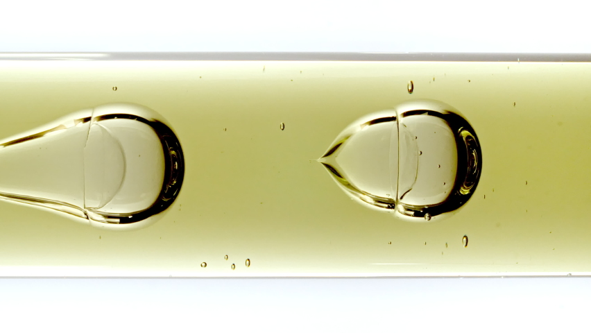 Transparent Cosmetic Gel Fluid With Molecule Bubbles and Oil Flowing in Glass Tube with Clear Liquid on White Background. Macro shot. Production Close-up. Slow Motion. Royalty-Free Stock Footage #1097073191