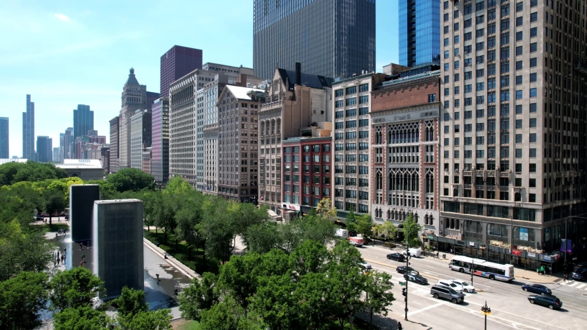 Reverse aerial showing Chicago cityscape around Millennium park with Cloud gate as public sculpture.