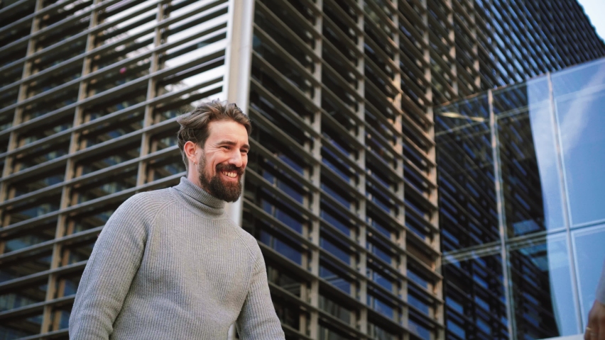 Two partners in casual clothes shaking hands while standing on city street. Man greeting and listening to the employer. Business Concept. High quality 4k footage