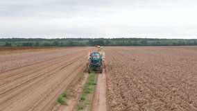 a blue tractor is carrying potatoes. Harvesting period from the fields. The farmer is carrying potatoes grown in his field. fresh vegetables. tractor with trailer. 4k Aerial Footage