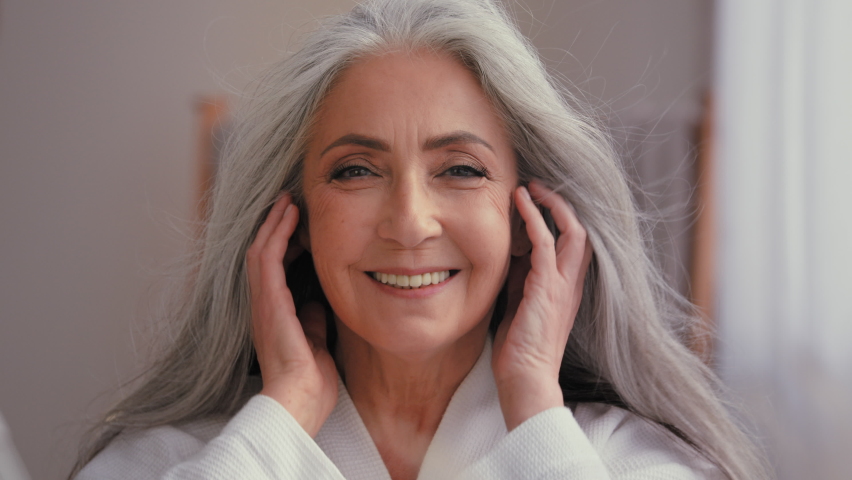 Female portrait close up headshot 60s old middle-aged mature senior aging Caucasian woman grandma senior older 50s lady model with long shiny smooth gray hair smiling looking at camera wind haircare Royalty-Free Stock Footage #1097088279